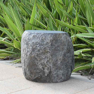 Elementi Boulder Seat in natural rock color placed beside the plants