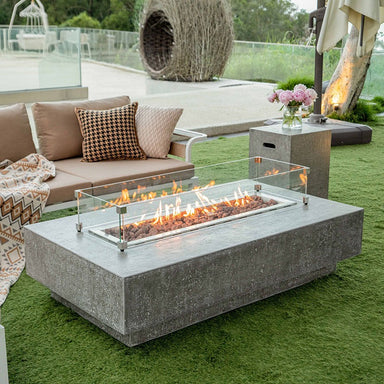 Elementi Hampton Fire Table in Light Grey showing its full flames with the optional windscreen