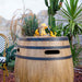 Elementi Napa Fire Column placed outdoors looking like a barrel with plants nearby