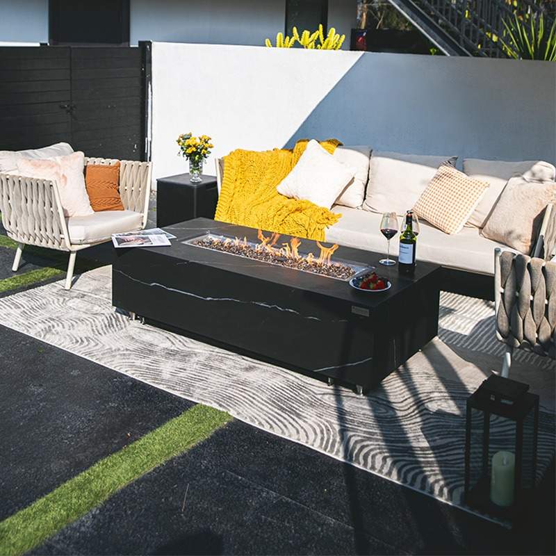 Elementi Plus Carrara & Varnain Slate Black showcasing its flames, placed outdoors witch couches around