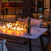 Elementi Plus Oslo Marble Porcelain Dining Table showcasing its flames to provide heat outdoors