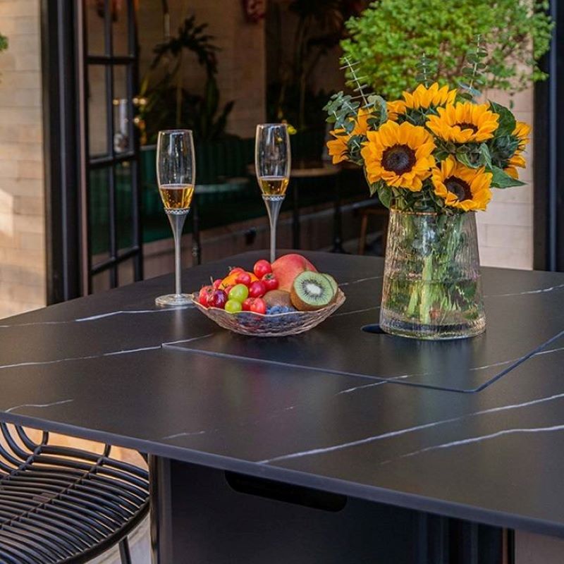 The Koln Marble Porcelain Bar Table by Elementi Plus in black function as a table placed outdoor