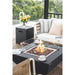 showcasing the flames of the Aurora Fire Pit in black with the optional windscreen